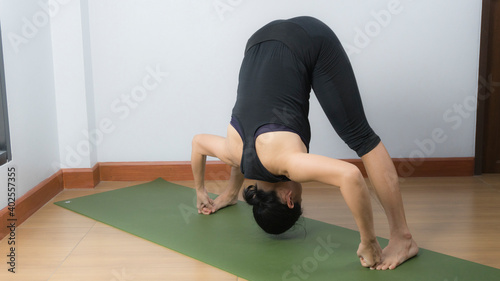 Asian young woman wear a black yoga outfit . Practicing yoga Standing Asanas Action PRASARITA PADOTTANASANA D .Home yoga practice on white background