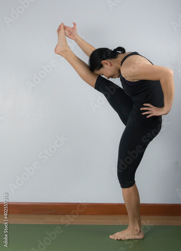 Asian young woman wear a black yoga outfit . Practicing yoga Standing Asanas Action UTTHITAHASTA PADANGGUSTHASANA A (Extended hand to big toe pose) .Home yoga practice on white background