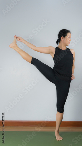 Asian young woman wear a black yoga outfit . Practicing yoga Standing Asanas Action UTTHITAHASTA PADANGGUSTHASANA B (Extended hand to big toe pose) .Home yoga practice on white background photo