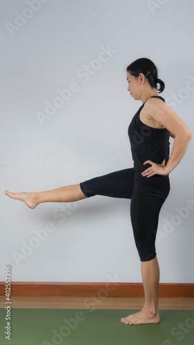 Asian young woman wear a black yoga outfit . Practicing yoga Standing Asanas Action UTTHITAHASTA PADANGGUSTHASANA D (Extended hand to big toe pose) .Home yoga practice on white background