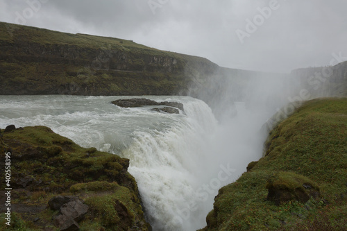 People visiting and experiencing the power of popular tourist destination - Gullfoss waterfall on Hvita river in Iceland