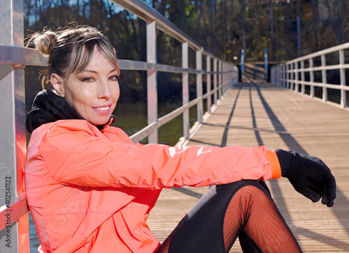 Young athlete woman relaxes and rests on the walkway of a bridge