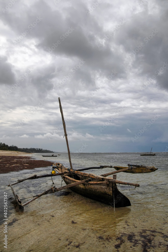 Fototapeta premium Traditional kenyan fishing boat in Indian ocean on the background of dramatic cloudy skyt. Surroundings of Mombasa, Kenya.