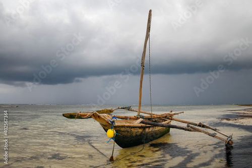 Traditional kenyan fishing boat in Indian ocean on the background of dramatic cloudy skyt. Surroundings of Mombasa, Kenya. photo