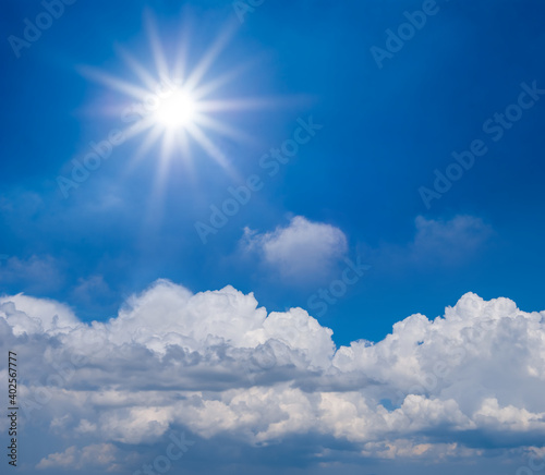 sparkle sun above dense cumulus clouds on the blue sky background  summer concept scene