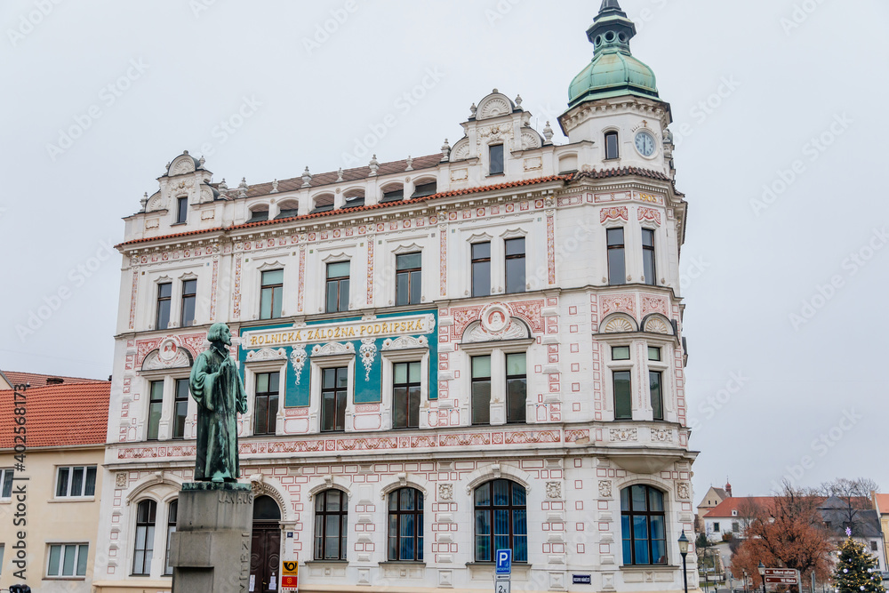 Neo-Renaissance white building of the former Farmers' bank Podripska with red sgraffito mural decorated plaster and statue of Jan Hus in Roudnice nad Labem, Bohemia, Czech Republic