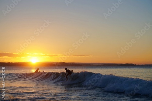 A silhouette of a young male surfer riding a small wave at sunset - Gold Coast photo