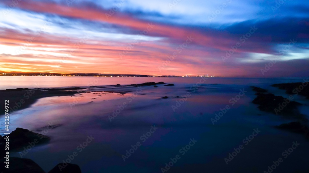 Long Exposure - A colourful sunset bathes the ocean in bright colours at Snapper Rocks at high tide - Gold Coast