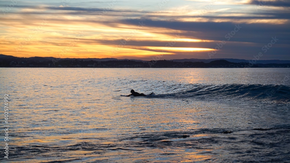 A longboarder paddles for a small colourful wave at Snapper Rocks - Australia