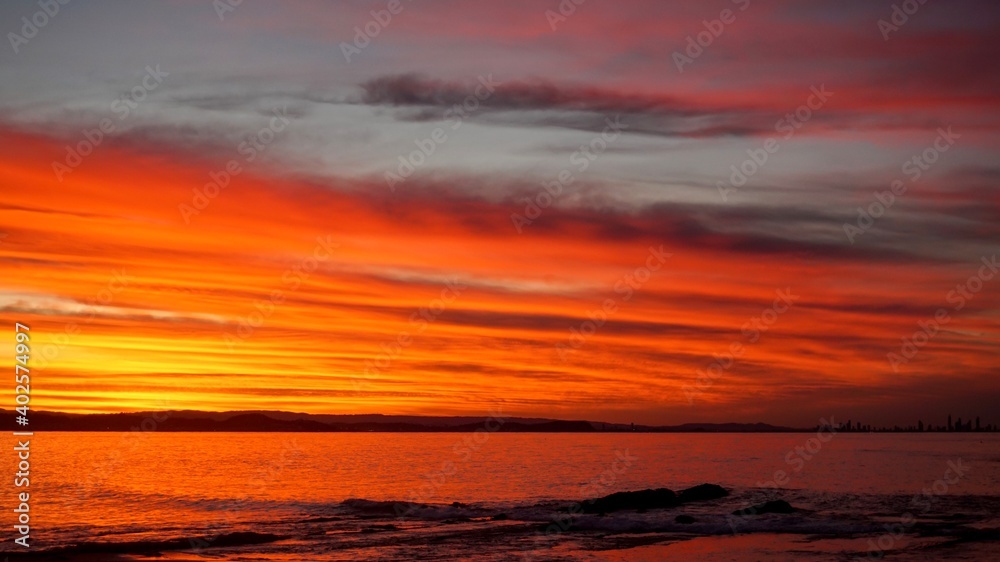 A vibrant sunset over the Gold Coast bathes the sky in bright colours