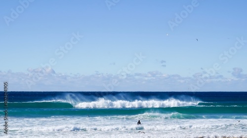 A surfer begins a heavy paddle out in rough waters with big waves