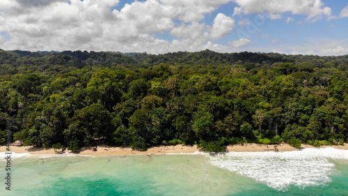 Looking down at a tropical island coastline. Turquoise waters lap golden sands infront of a rainforest © William