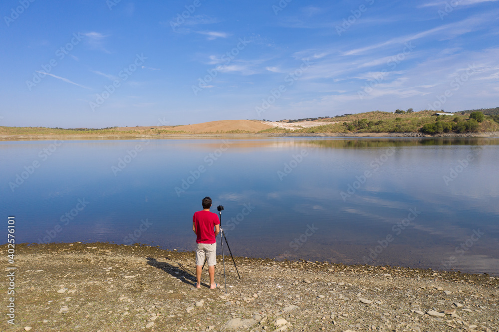 Drone shot of a caucasian man photographing a Landscape with a lake and reflection in Alentejo, Portugal