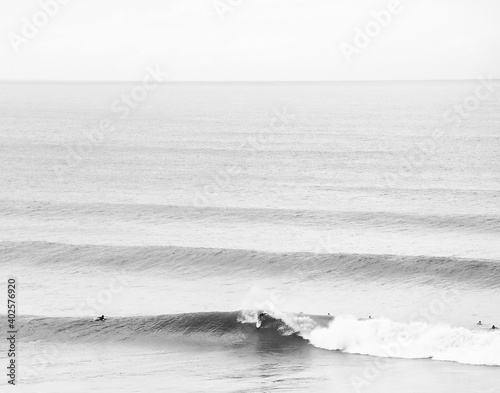 Black and white minimalistic surf background. A surfer does a big top turn in overhead waves