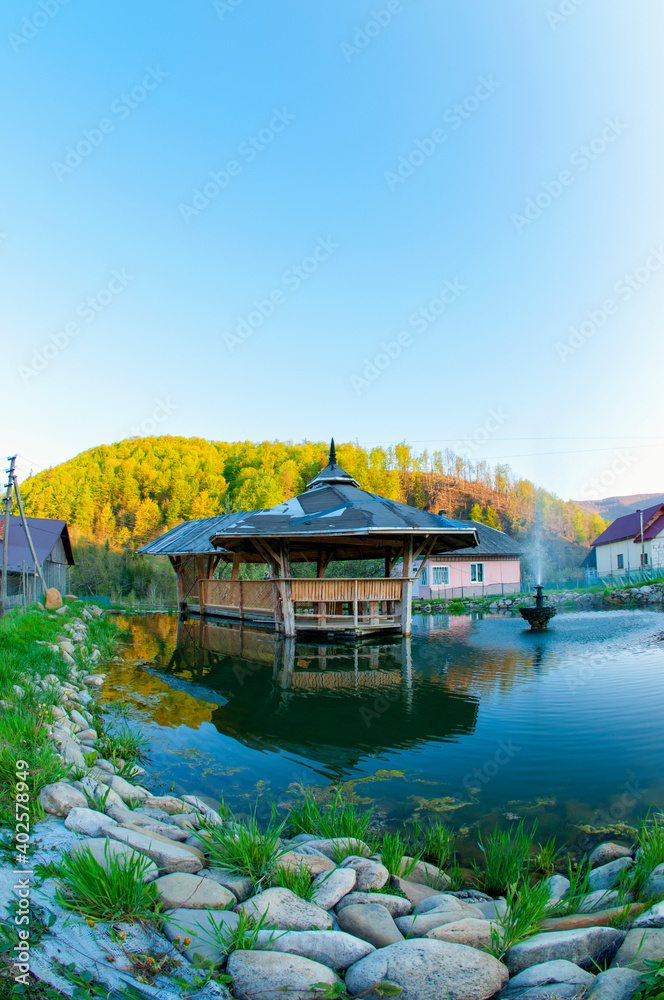 Fototapeta premium gazebo over the water in the mountains under the autumn sun