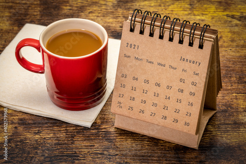 January 2021 - desktop spiral desktop calendar with a cup of coffee, time and business concept