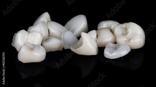 a set of different dental veneers in a chaotic manner, on black glass with reflection