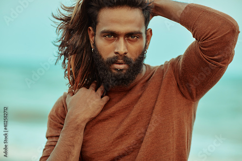Long hair bearded young man portrait enjoying breezy wind in sea background.
