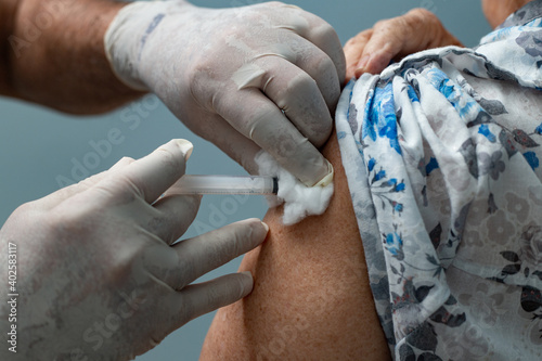 Vacinação. Detalhe de mãos com luvas de pessoa a vacinar outra pessoa. photo