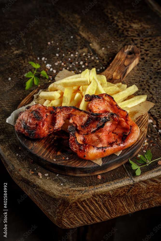 Grill house concept. Grilled, roasted, fried tasty pork meat with french fries on the old wooden cutting board. Grill house concept. Grilled, roasted, fried tasty pork meat with french fries on the old wooden cutting board.