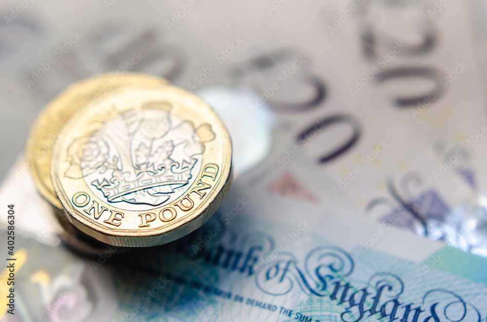 British money. Macro photo of One Pound coins and the British pound banknotes of different denomination. British money. Macro photo of One Pound coins and the British pound banknotes of different denomination.