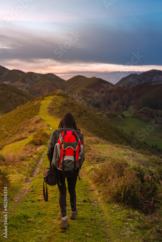 vertical stock photograph of unrecognizable hiker with red backpack performing a mountain route. outdoor sports.