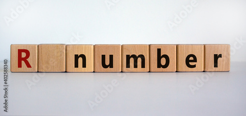 R - reproduction number symbol. Wooden cubes with word R - reproduction number on beautiful white background. Covid-19 pandemic R - reproduction number concept. photo