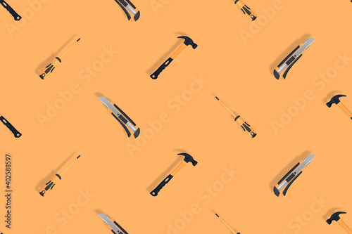 Tools seamless pattern. Tools: hammer, screwdriver and knife on an orange background.