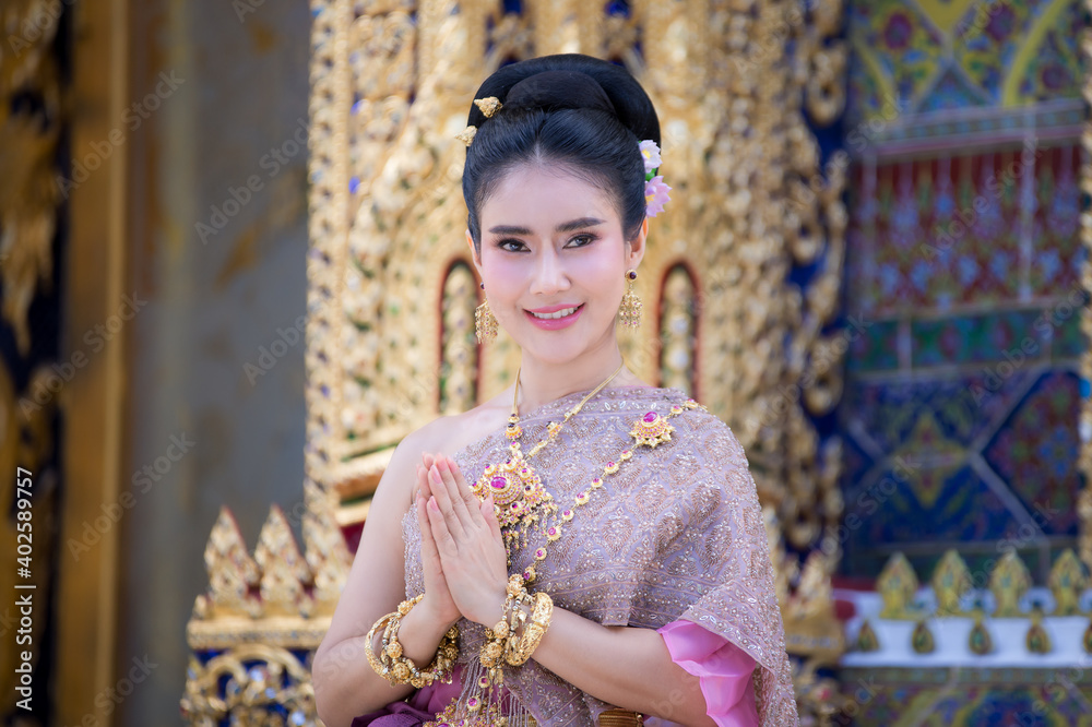 Beautiful Thai woman wearing a Thai Chitralada dress holds a garland in her hand in a Buddhist temple in Thailand which is architecturally beautiful. Beautiful Thai woman wearing a Thai Chitralada dress holds a garland in her hand in a Buddhist temple in Thailand which is architecturally beautiful.