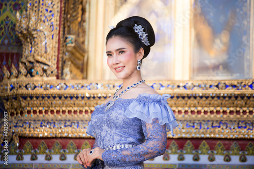 Beautiful Thai woman wearing a Thai Chitralada dress holds a garland in her hand in a Buddhist temple in Thailand which is architecturally beautiful. photo