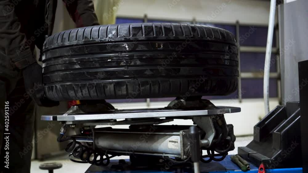 Mechanic changing car tire, close up. Footage. Worker wearing uniform