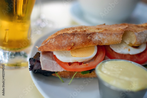 Foto A ham club sandwich and beer at an outdoor cafe in Paris France with tomatoes, hard boiled egg, on a fresh baguette