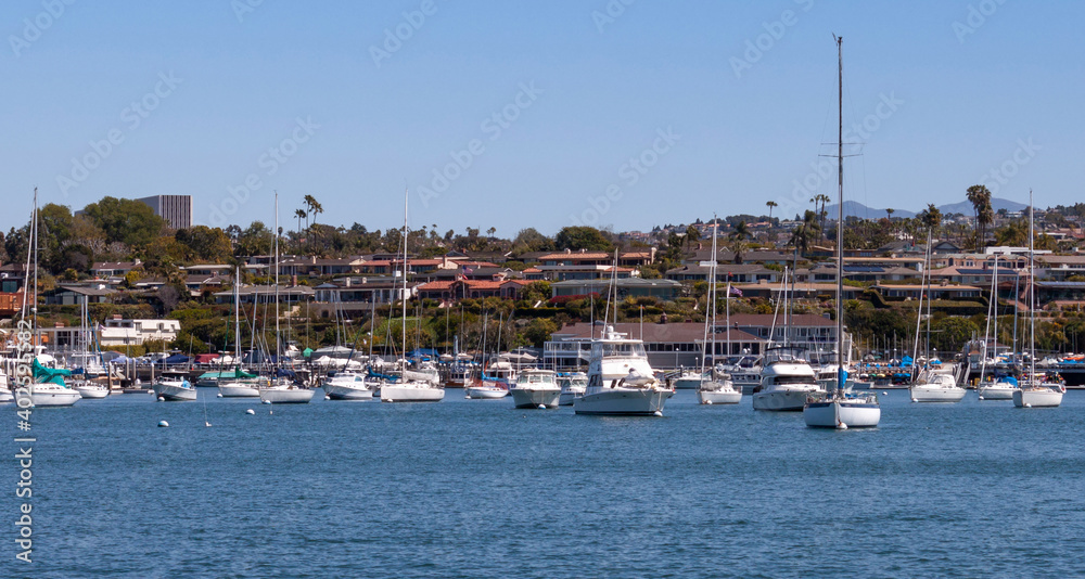 boats moored in Newport Beach harbor in California on a sunny day city skyline in background