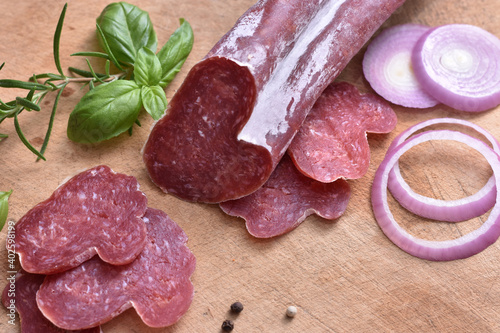 Slices of delicious spanish sausage fuet on the wooden natural kitchen board closeup. Love food concept. Traditional Spanish sausage. Variety of dry cured chorizo. Heart shaped sausage.