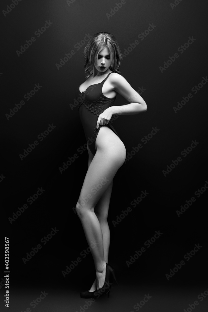 Monochrome portrait of a sexy girl, glamorous stylish fashion model in a red underwear posing stands on dark background. Fall fashion. Monochrome portrait of a sexy girl, glamorous stylish fashion model in a red underwear posing stands on dark background. Fall fashion.