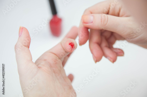 Girl paints nails with red varnish on a white background. close-up 