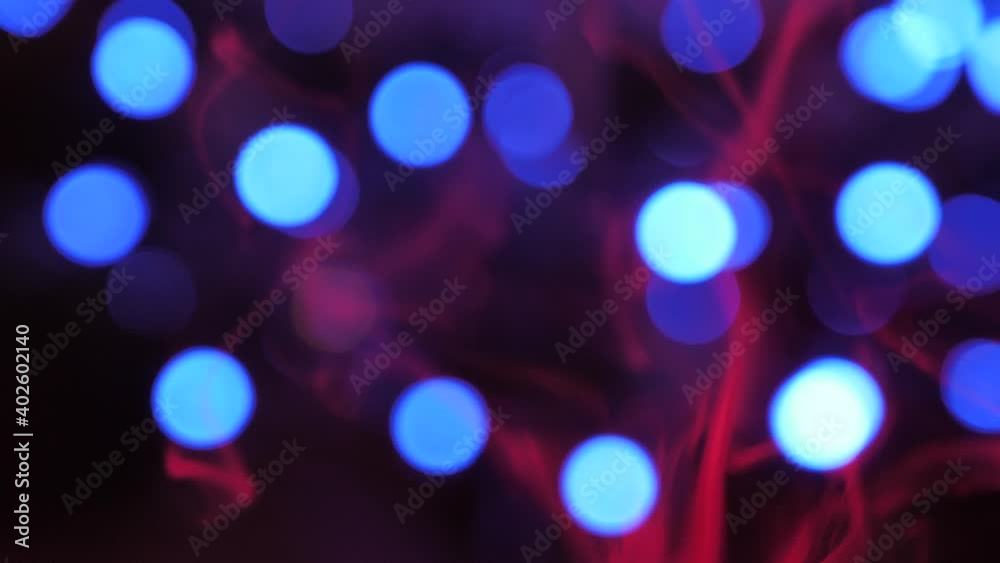 Red smoke moves up slowly, round lights move in the background, smoke and lights are blurred Red smoke moves up slowly, round lights move in the background, smoke and lights are blurred