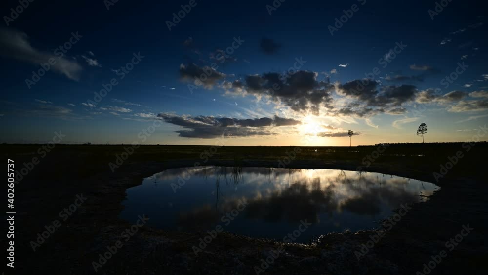 Timelapse of sunset over Hole-in-the-Donut habitat restoration area in Everglades National Park, Florida reflected in water of exposed solution hole 4K.