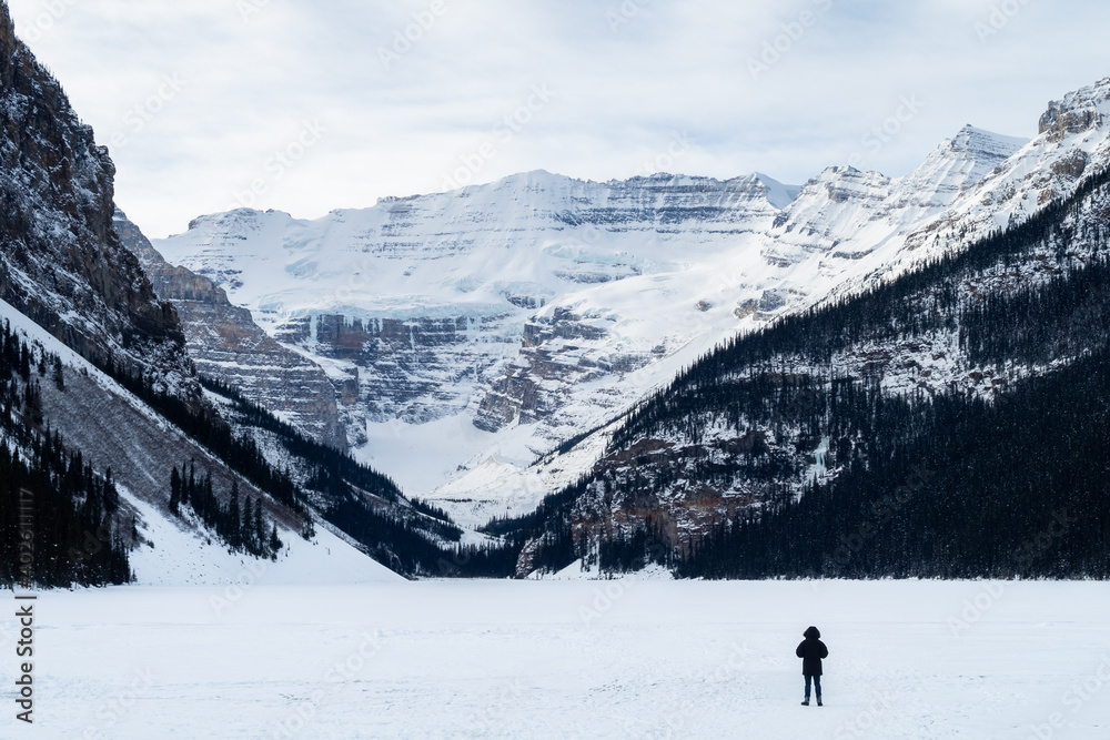 Back view of a man walking alone on the frozen Lake Louise, Canada