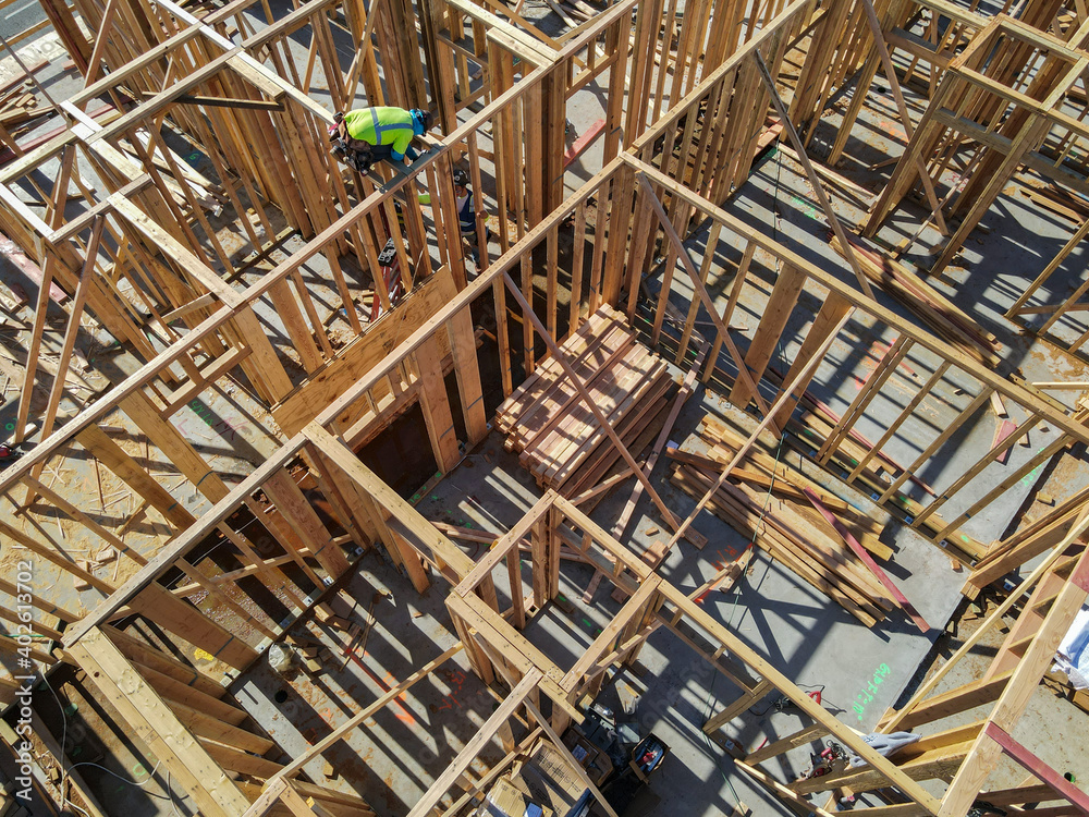 Aerial view of a new building being framed by carpenters. Worker builder working on building structure on construction site.