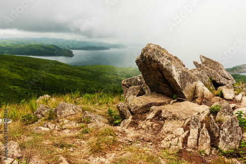 Bay of the sea and large rocks from the hilltop of the mountainous coast, summer landscape and seascape in cloudy cloudy weather.