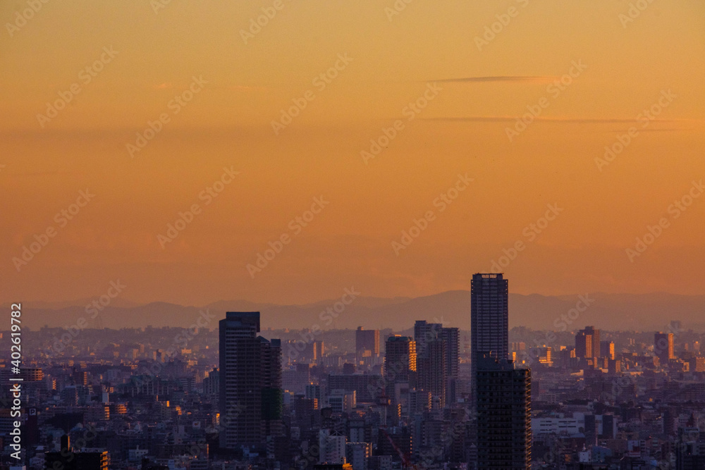 神戸三宮の山手、諏訪山公園ヴィーナスブリッジｋらの夜明け。オレンジ色に染まる空に浮かぶ高層ビル