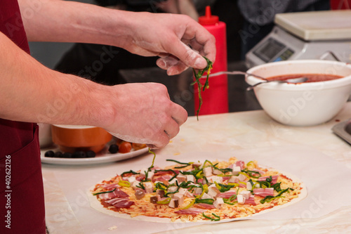 Fototapeta Naklejka Na Ścianę i Meble -  The process of making pizza. Hands of chef baker making pizza at cafe kitchen