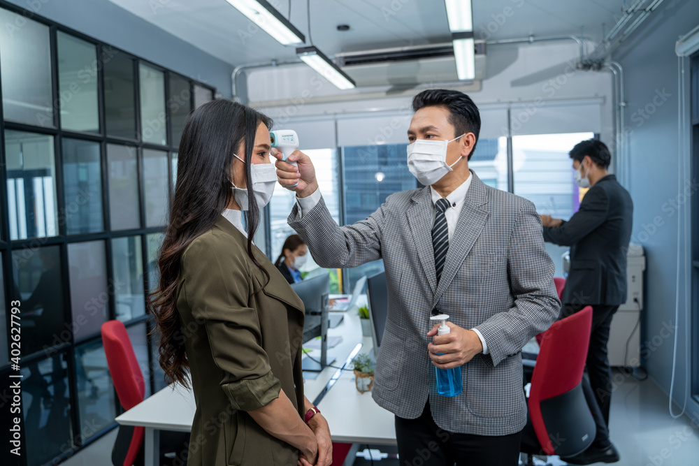 Business people wearing protective mask to Protect Against Covid-19 scan temperature before working in office to protect infection from coronavirus covid-19,Social distancing concept. Business people wearing protective mask to Protect Against Covid-19 scan temperature before working in office to protect infection from coronavirus covid-19,Social distancing concept.