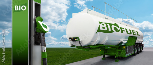 Tank trailer with biofuel and filling station on the background of a green field and blue sky photo