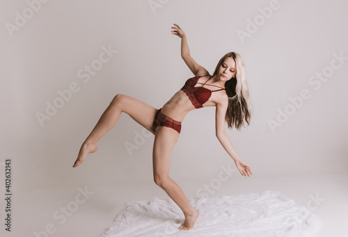 Woman in underwear sits in the studio against white background.