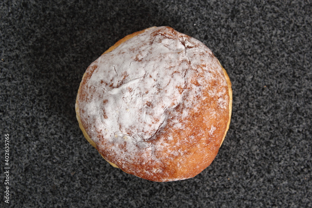 Doughnut without a hole filled with jam with sugar on top Doughnut without a hole filled with jam with sugar on top