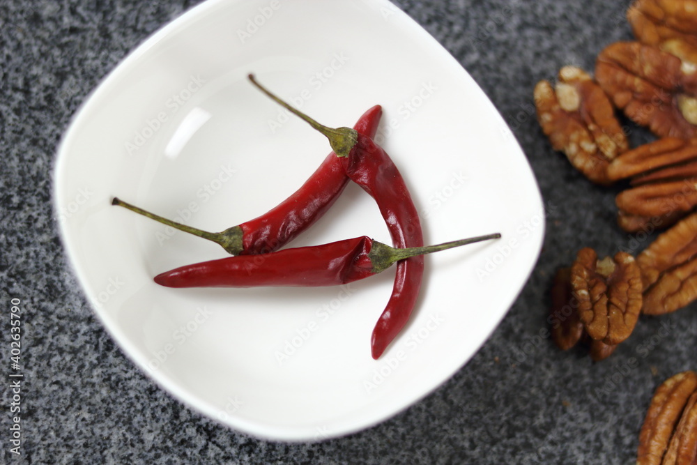 Chili pepper in bowl and pecan nuts Chili pepper in bowl and pecan nuts