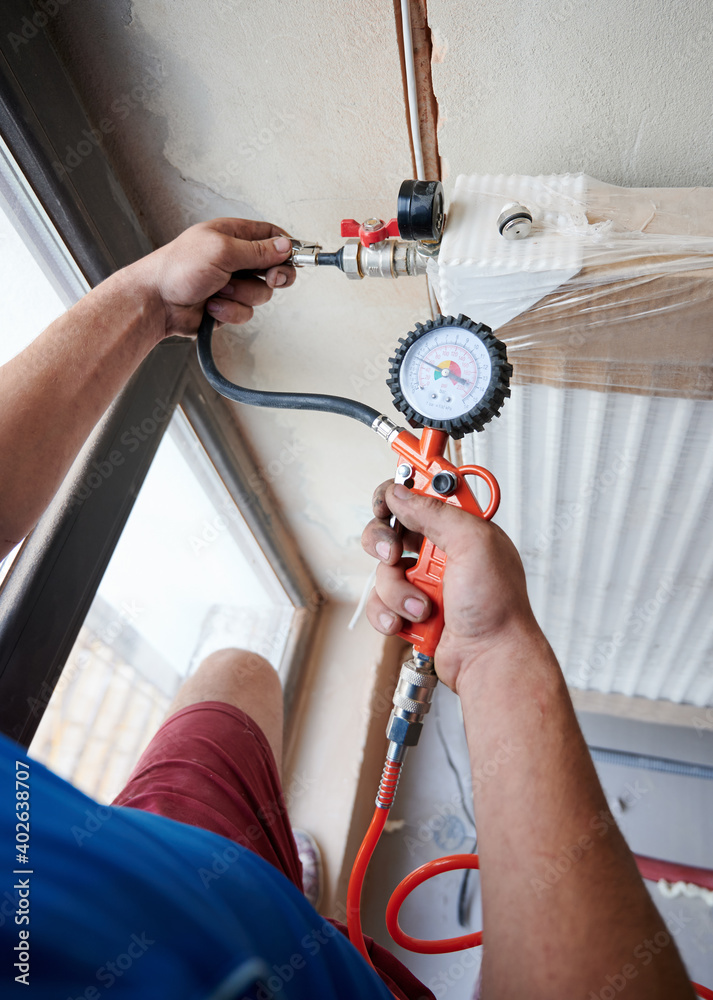 Close up plumber filling pipes with pressurized air to inspect for