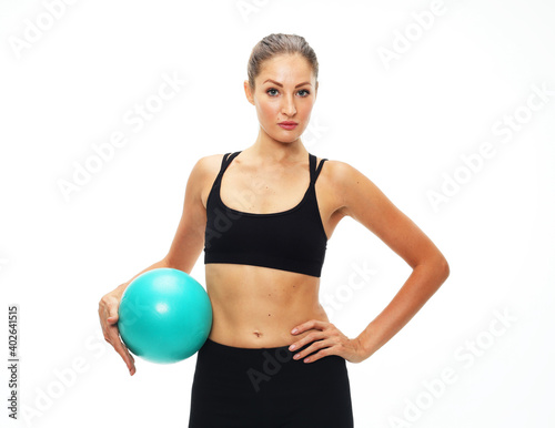 Young fit adult woman doing yoga exercise workout with gymnastics ball.